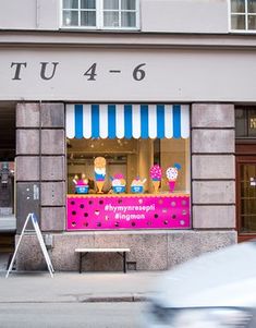 a store front with a pink and blue awning on the side of it's window