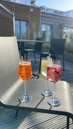 two glasses of wine sitting on top of a table next to each other with drinks in them