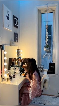 a woman sitting at a vanity in front of a window