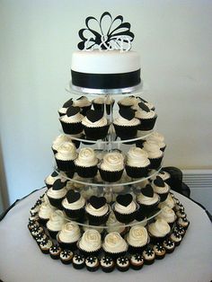 a three tiered cake with cupcakes on the bottom and black and white frosting