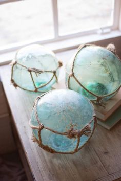 three blue glass bowls sitting on top of a wooden table next to a book and window