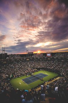 a tennis match is being played in an empty stadium at sunset with the sun going down