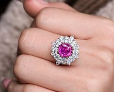 a woman's hand holding a pink and white ring with diamonds on the middle