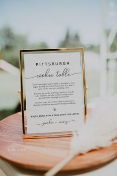 a sign that is sitting on top of a wooden table next to a white feather