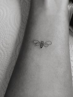 a black and white photo of a bee tattoo on the ankle, it looks like an insect