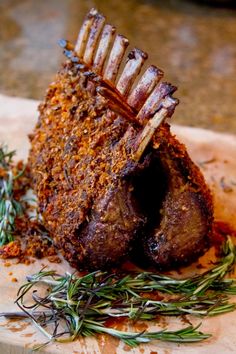 a piece of meat sitting on top of a wooden cutting board next to some herbs