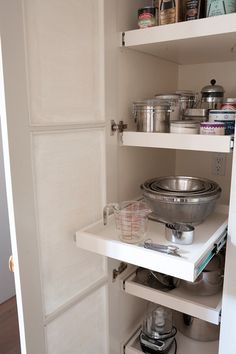 an open pantry door with pots and pans in it