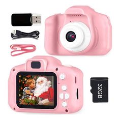 a pink digital camera sitting next to a memory card and charger with a christmas ornament on it