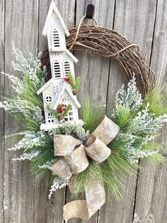 a wreath is hanging on the side of a fence with a birdhouse and evergreens