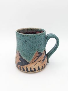 a ceramic mug with mountains and trees on the inside is sitting in front of a white background