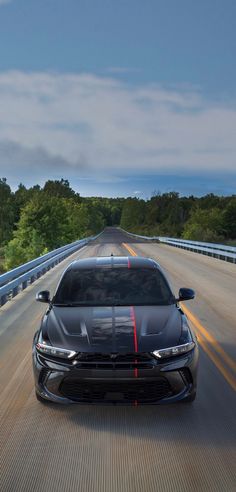 the front end of a black car driving down a road