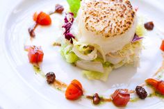 a white plate topped with food and garnished with tomatoes, lettuce and other vegetables