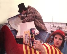 a man and woman sitting on the back of a boat with books in their hands