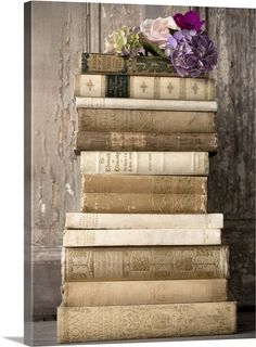 a stack of old books with flowers on top