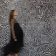 a blurry photo of a woman walking in front of a wallpapered background