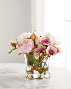 pink and white flowers in a glass vase on a marble countertop with sunlight coming through the window