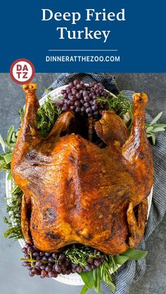 a roasted turkey on a platter with grapes and herbs in the background text reads deep fried turkey dinner