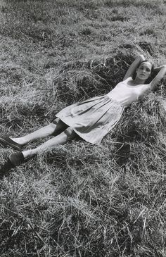 an old photo of a woman laying on the ground with her arms behind her head