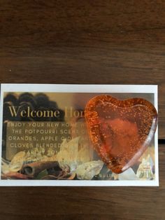 a heart shaped piece of candy sitting on top of a wooden table next to a business card