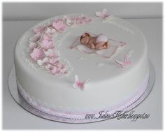 a white cake with pink frosting and baby's photo on top is shown