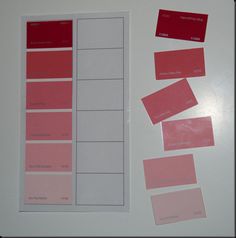 several different shades of pink and red on a white surface with labels attached to them