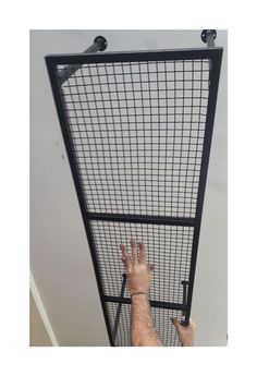 a man reaching up to the ceiling with his hand on an enclosure door that is open