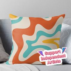 an orange and blue pillow with the words support independent artists in front of it on a couch