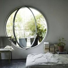 a bed sitting under a round window in a bedroom