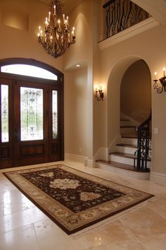 a foyer with chandelier, rug and stairs leading up to the entrance door