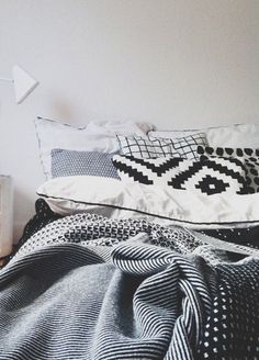 an unmade bed with black and white pillows