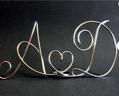 a metal wire sculpture with two hearts on it's sides and the word love spelled in cursive letters