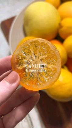 a person holding a piece of fruit in front of some lemons