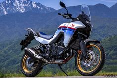 a motorcycle parked on the side of a road in front of mountains and snow capped peaks