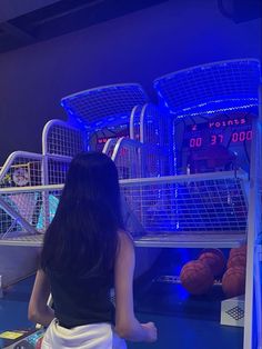 a woman sitting on the ground in front of some basketball hoops and ball cages