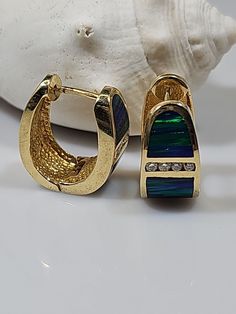 These stunning 14kt yellow gold earrings feature a beautiful black opal and eight diamonds with a total carat weight of .24ct. The opal is a gorgeous shade of blue and is cut to a very good grade. The earrings are cuff style and measure 3/4 inch in length. The diamonds have a slight inclusion clarity grade (SI2) and are secondary to the main opal stone. These earrings are perfect for any occasion and would make a great addition to anyone's jewelry collection. Wt.17.20 grams Elegant Opal Huggie Jewelry, Elegant Opal Huggie Earrings, Yellow Gold Earrings, Opal Stone, Yellow Gold Earring, Good Grades, Black Opal, Fine Jewellery Earrings, Shades Of Blue