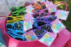 there are many pairs of sunglasses on display in the pink pail with tags attached to them