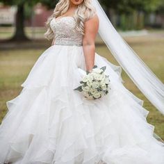 a woman in a wedding dress is posing for the camera with her veil flying over her head