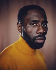 a close up of a person wearing a turtle neck sweater and looking at the camera