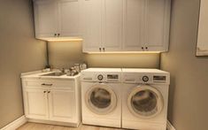 a washer and dryer in a room with white cupboards on the walls