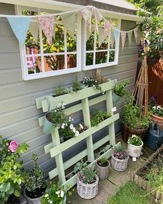 an outdoor garden area with potted plants and hanging bunting flags in the window