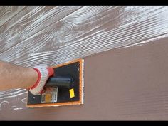 a person using a paint roller on wood planks