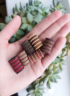 four small knitted rings sitting on top of a person's hand next to a succulent plant