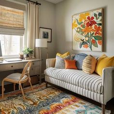 a living room filled with furniture and a painting hanging on the wall over a window