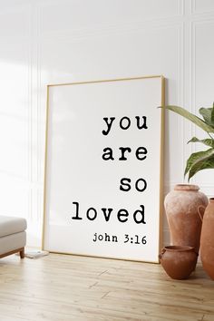 a white framed poster with the words you are so loved on it next to two vases