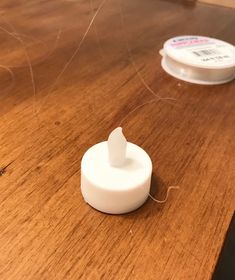 a white object sitting on top of a wooden table next to a container of glue