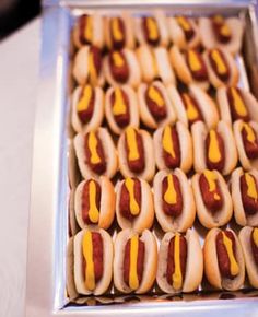 hotdogs with mustard and ketchup are arranged in rows on a tray