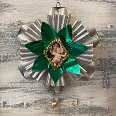 an ornament hanging on the side of a wooden wall with a green flower