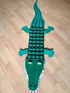 a paper cut out of a green alligator on a wooden floor