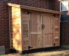 a wooden storage shed sitting next to a brick building