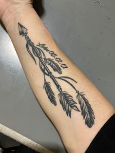 a woman's arm with an arrow and leaves tattoo on the left side of her arm